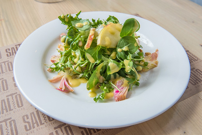 a plate of salad with fruit and sauce